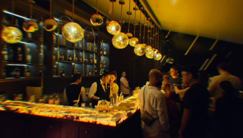 AMBER's bartenders behind the illuminated bar under gold pendant lights